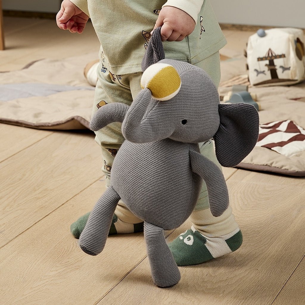 Kind houdt Fille Gebreide Olifant - Biologisch Katoen vast, perfect als knuffelvriend. Grijze olifant met CE-keurmerk en gerecyclede vulling.